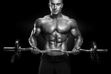 Fototapeta na wymiar Portrait of handsome bodybuilder performing the biceps curl with EZ curl bar at gym. Perfect physique athletic young man with six pack, perfect abs, shoulders, biceps, lats and chest.