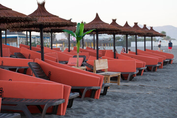 Fototapeta na wymiar Straw umbrella on the beach with sun loungers on the coast of Malaga