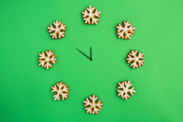 Top view of Christmas watch with gingerbread snowflakes on the green  background