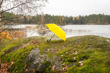Yellow umbrella. A beautiful large bright yellow umbrella lies on the shore of the lake. Autumn landscape on a cloudy rainy day. Lake shores.