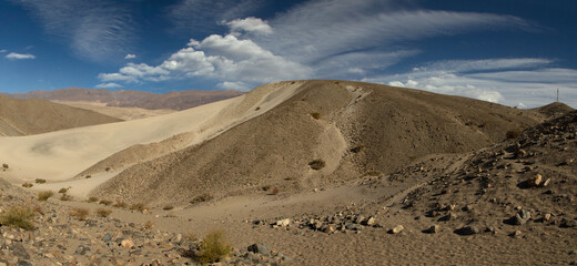 Desert landscape. Panorama view of the beautiful yellow sand dunes, rocky and arid hills, under a summer blue sky.