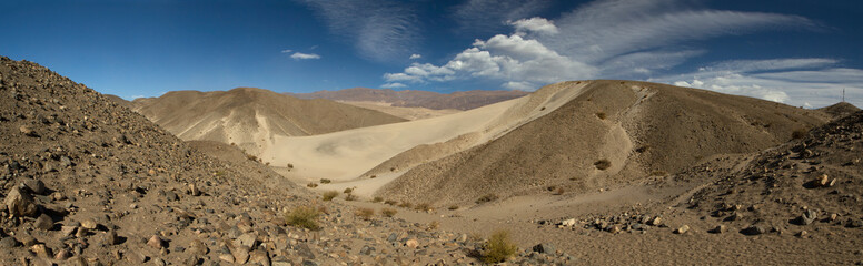 Desert landscape. Panorama view of the beautiful yellow sand dunes, rocky and arid hills, under a summer blue sky.