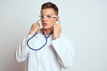 doctor in a medical gown with a stethoscope and glasses on a light background cropped view portrait