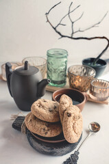 Almond and chocolate homemade cookies on the table with a ceramic Cup of tea and a kettle