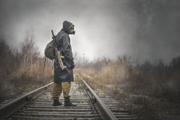 A post apocalypse soldier with a rifle is walking on the railroad.