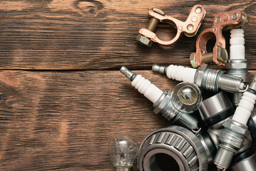A car spark plug and other spare parts on the wooden workbench background with copy space.