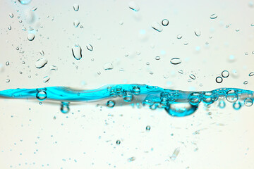 Nahaufnahme einer blauen Wasseroberfläche mit Wassertropfen und Luftblasen.