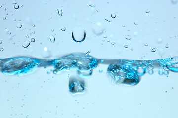 Nahaufnahme einer blauen Wasseroberfl&auml;che mit Wassertropfen und Luftblasen.