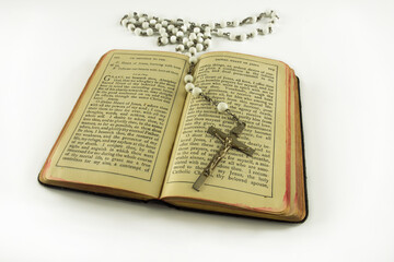 Opened catholic holy prayer book Treasury of the Sacred Heart and white beads crucifix with holy cross isolated on a white background