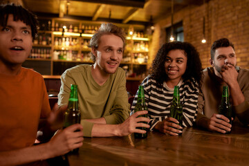 Keep calm and cheer on. Friends in the bar watching sports match on TV together, drinking beer and cheering for team. People, leisure, friendship and entertainment concept