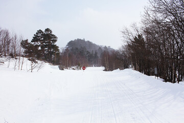 Stop sign located in mountain and forest snowy area.  Snowy forest. Hiking in the mountains. Travel to winter Russia. Lago-naki