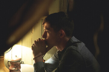 A man in a shirt is sitting in the house. Photo through the window.