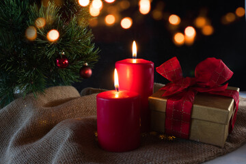 Red advent candles and a gift box with christmas ornaments and festive bokeh. Atmospheric christmas...