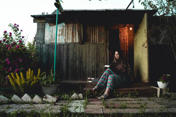 young beautiful woman in sitting on the porch of the house and reading books.