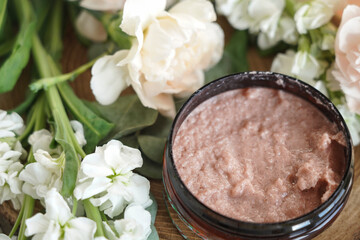body scrub in a jar on a background of flowers