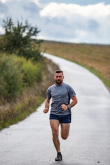 Fototapeta premium young man running on country road