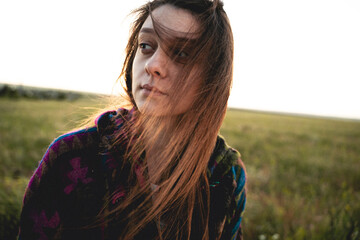 young woman in an Indian poncho in a green field. Long hair