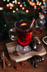 Mulled wine glass with cinnamon and orange. Cookies and fir branches.