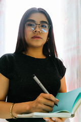 woman with glasses writing in a notebook