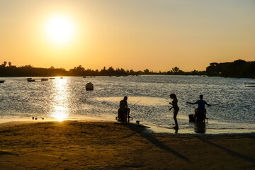 Naklejka na ściany i meble people fishing in the lagoon at sunset