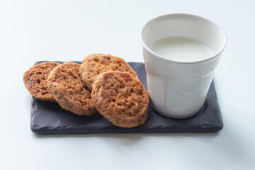 Porcelain glass of milk with cockies on a gray board, white isolated background 