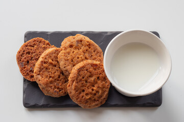 Porcelain glass of milk with cockies on a gray board, white isolated background  and top view