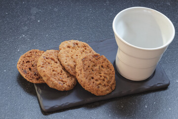 white porcelain glass with milk and cookies on a dark background