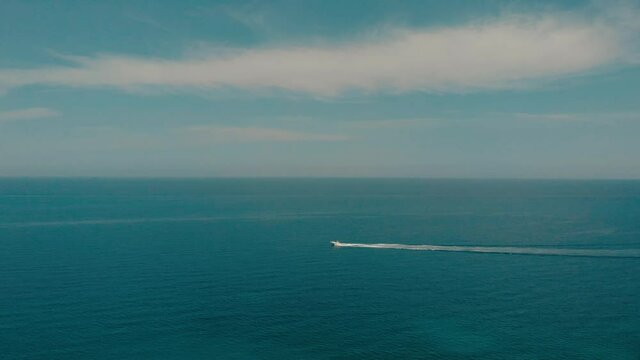 The sea and the sky. A small boat sails on the calm bkue surface of the sea.