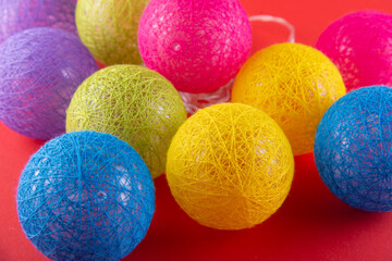 Colored knitted Christmas garland. Heap of red, purple, blue, yellow, green balls lying on red background