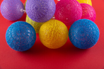 Heap of different color knitted balls as holiday garland lying on red background