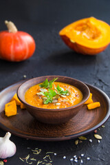Delicious healthy pumpkin soup, herbs, and ingredients for the dish. Creative atmospheric decoration