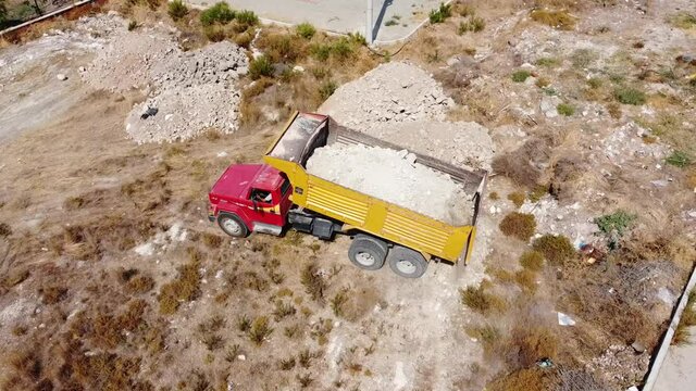 A dump truck dumps ballast on a construction site.