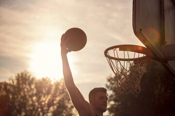 Young man jumping and making a fantastic slam dunk playing streetball, basketball. Urban authentic. © FS-Stock