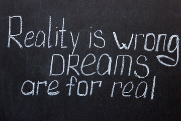 Chalkboard text Reality is wrong, dreams are for real. Motivational lettering