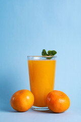 A glass of tangerine juice in a clean light blue background