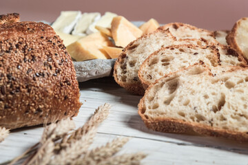 Sliced rustic bread and cheese on a white wooden board. Healthy food and farming concept