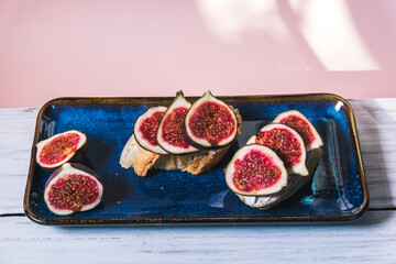 Bruschetta of baguette, cheese and figs are on a plate on the table. The concept of minimalism in...