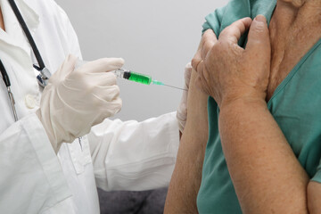 Senior woman receiving vaccine. Medical worker vaccinating an elderly patient against flu, influenza, pneumonia or coronavirus.