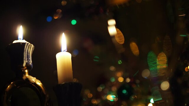 Christmas, New year, Holidays. Two candles against a background of flickering colored lights. Background video. Close up.