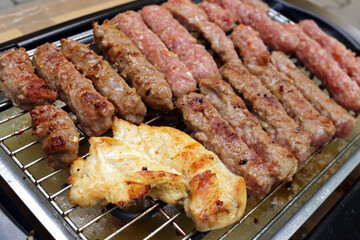 Kebab and chicken breast meat grilling on a electrical grill.