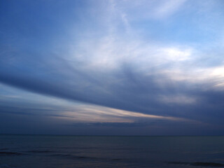 Dreamy ocean dusk with blowing clouds and rising tide