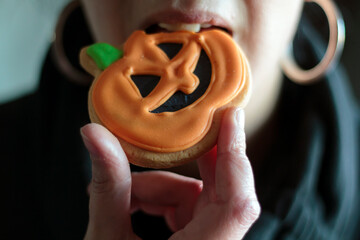 Close-up of woman eating a halloween pumpkin biscuit