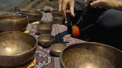 Asian guy playing Tibedt singing copper cups on a viewing mountain