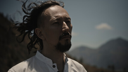 Asian guy playing Tibedt singing copper cups on a viewing mountain