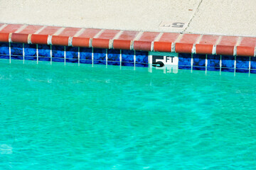 Swimming pool depth marker identifies the water depth for swimmers. Five feet depth sign