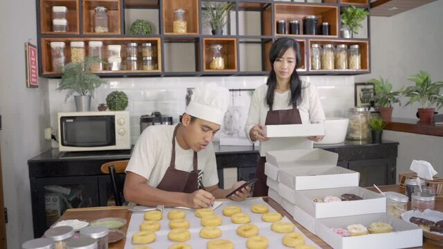 portrait of asian couple working on their small business by making handmade food bakery and donuts product at home