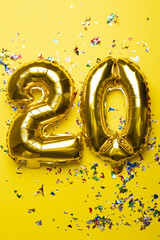 Number 20 from golden foil balloon and confetti