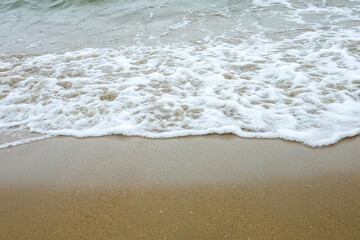 Waves breaking on shore of the sea. closeup of sea foam on wet sand