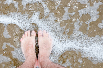 mans feet in water with waves lapping