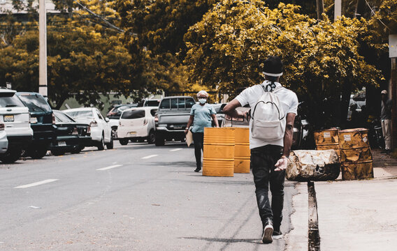 thug-looking man walking through the city streets with a backpack to the park